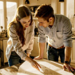 Crédito personal para obras en casa: ¿vale la pena? Pareja planeando reformas en su casa con plantas y herramientas sobre la mesa.