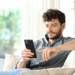 Hombre comparando préstamos personales desde su móvil en casa