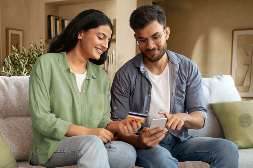 Pareja revisando un crédito personal para pagar deudas usando el móvil y una tarjeta bancaria