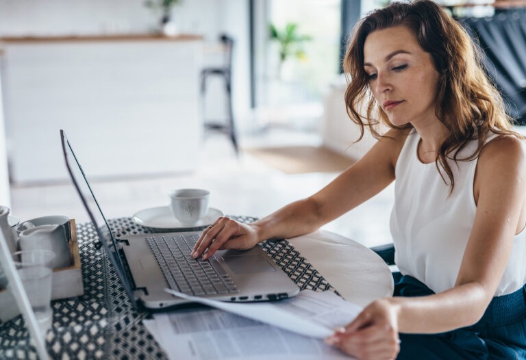 Mujer revisando su nómina en portátil antes de solicitar un préstamo con ASNEF en España
